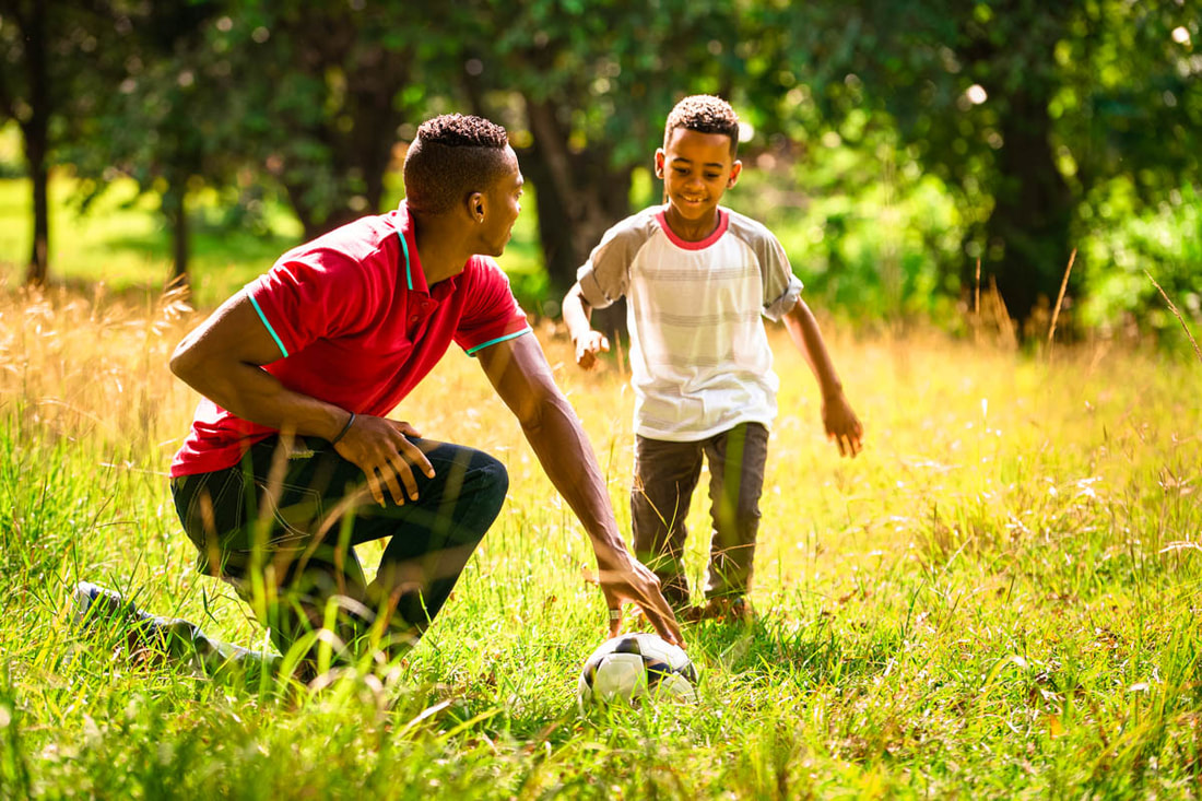 Padre e hijo jugando al fútbol en un día soleado
